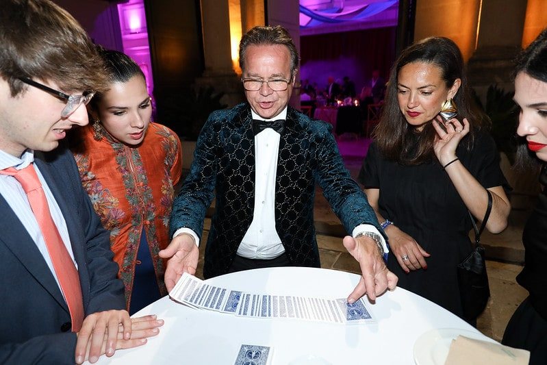Cards spread across a table with guests standing around it
