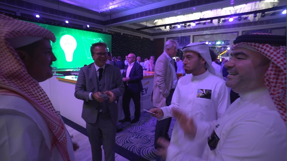 Guests at a hotel reception watching cards change hands at arm's length